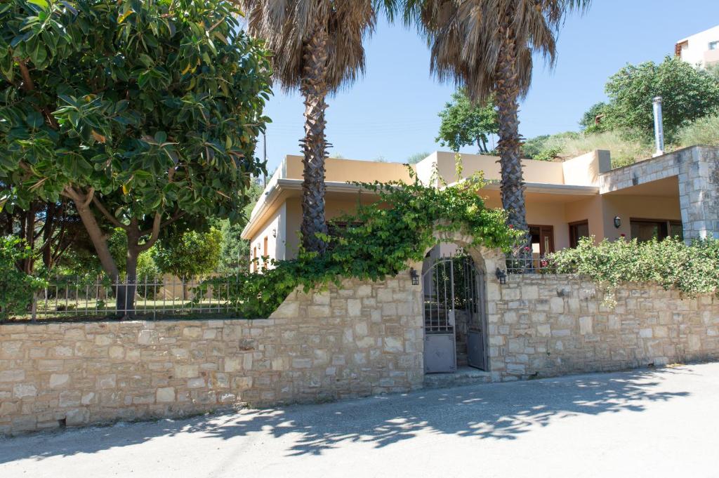 海若克利欧Heraklion Comfy House with Mountain View的石墙前有棕榈树的房子