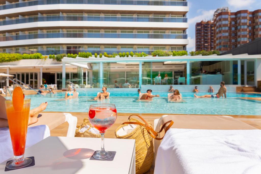 贝尼多姆Hotel Don Pancho - Designed for Adults的游泳池前的桌子和葡萄酒