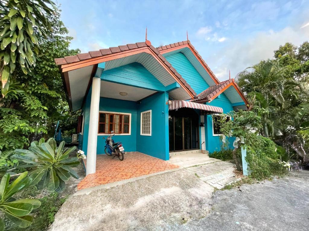 邦涛海滩Village House Wat 1的前面有一辆摩托车的蓝色房子