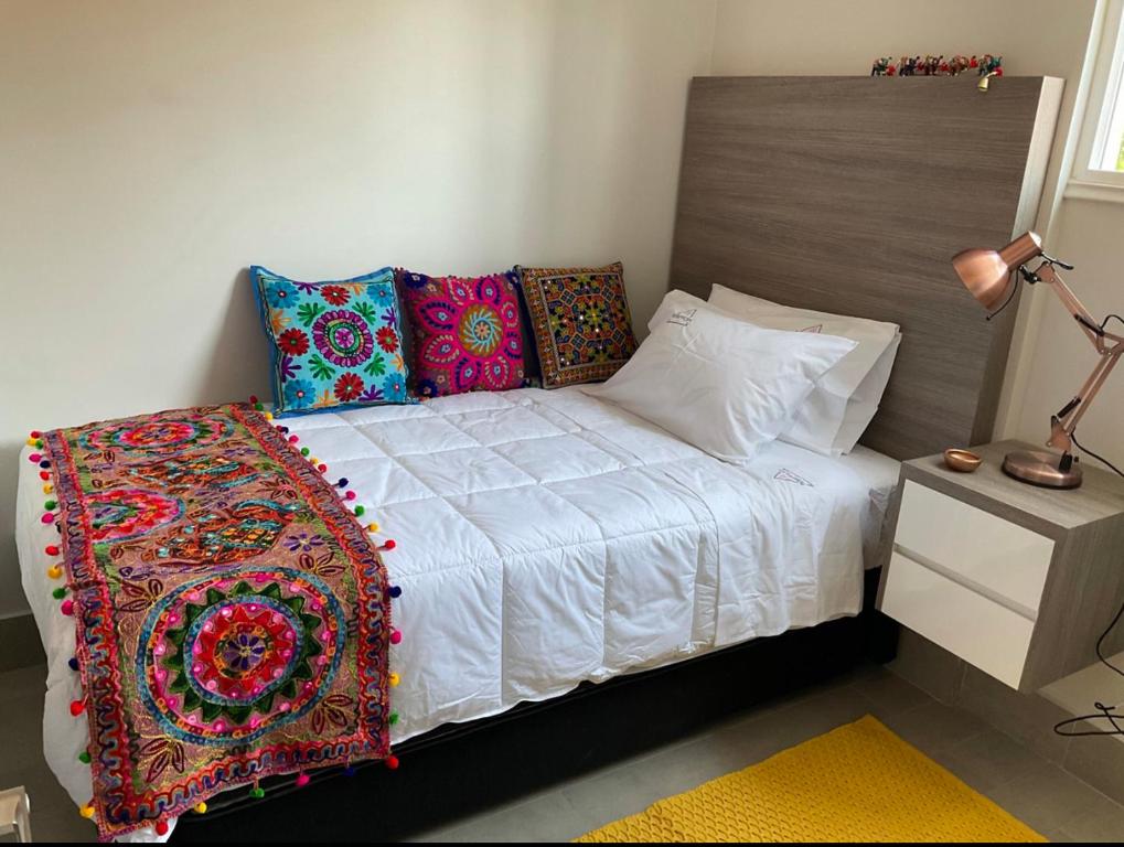 圣地亚哥Apartament Condo Amueblado, ENCOMENDEROS 200 El Golf, Las Condes Santiago con vista al Costanera Center的一间卧室配有带色彩缤纷枕头的床