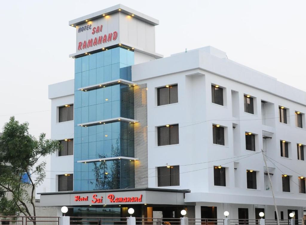 舍地Hotel Sai Ramanand的白色的建筑,上面有标志