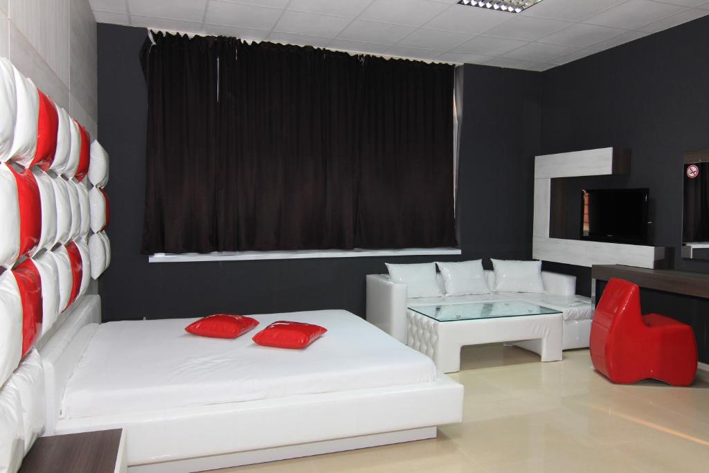 鲁塞Bedroom Place Guest Rooms的一间设有两张白色床铺和红色椅子的房间