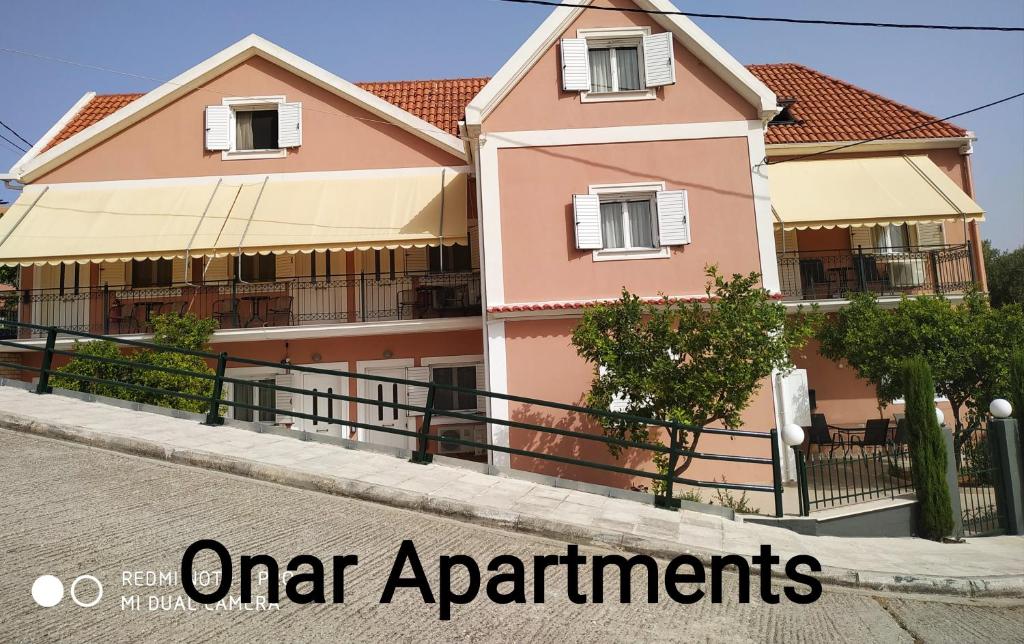阿尔戈斯托利翁Apartments Onar的一条街道上的粉红色房子,上面写着城市公寓的话