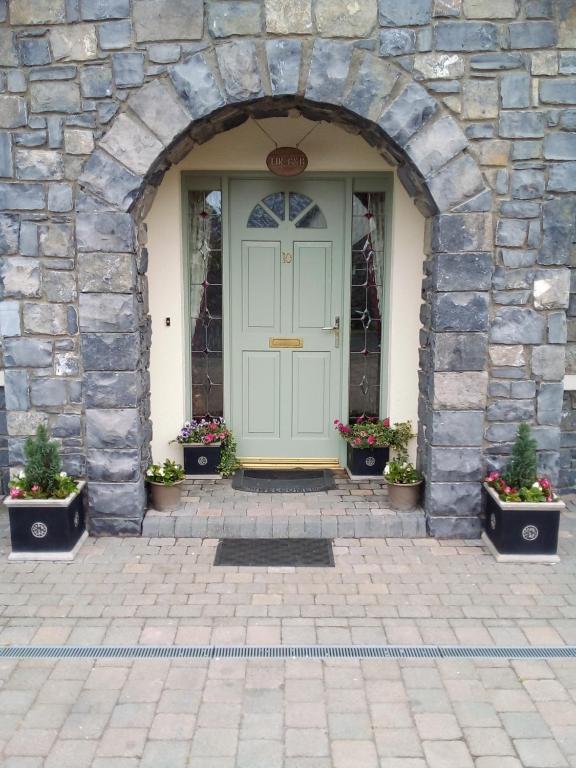 MultyfarnhamLír B&B的石头建筑中一扇门,里面栽有盆栽植物
