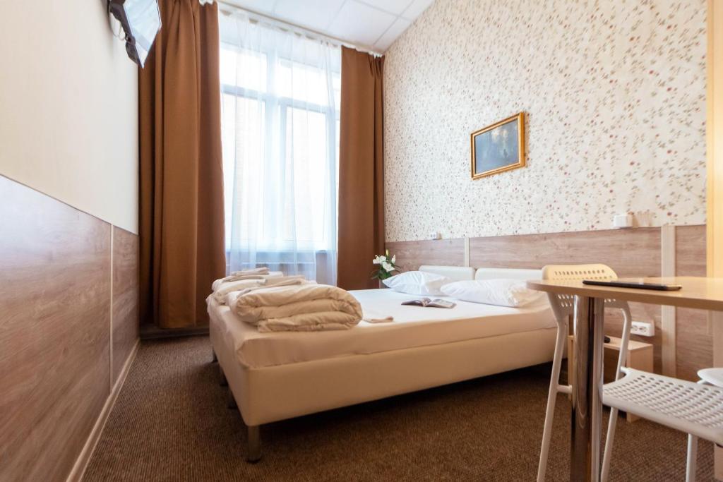 秋明柯洛斯酒店的一间卧室配有一张床、一张桌子和一个窗户。