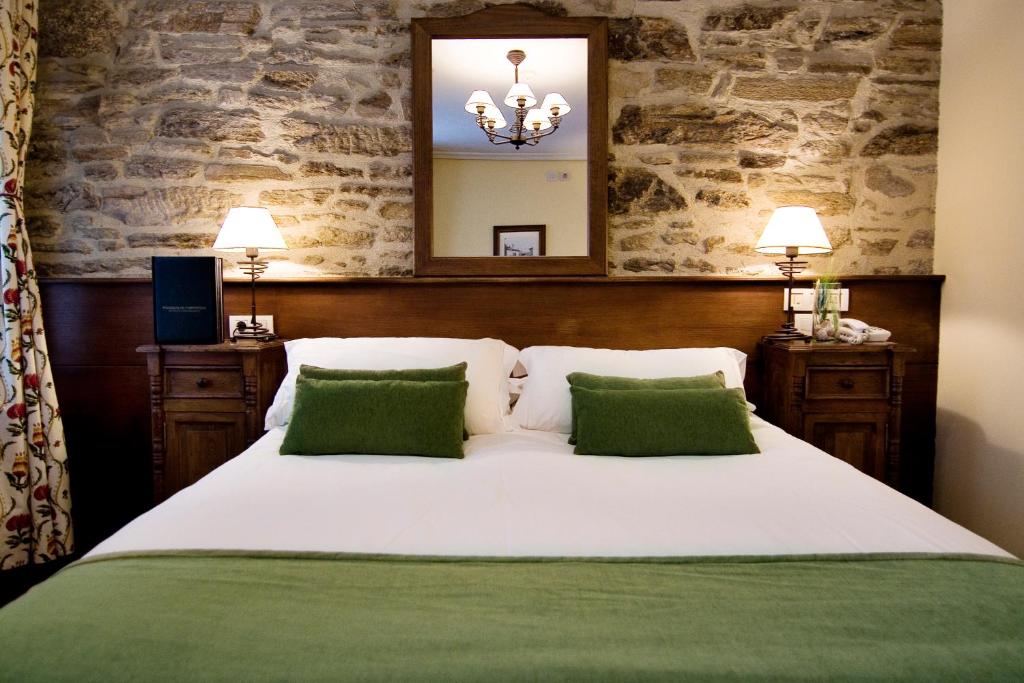 圣地亚哥－德孔波斯特拉San Clemente by Pousadas de Compostela的卧室配有一张带两个绿色枕头的大型白色床