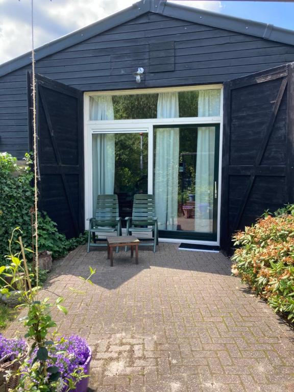 VriesAssen-Groningen-Saunacabine的黑色房子,配有两把椅子和一张桌子