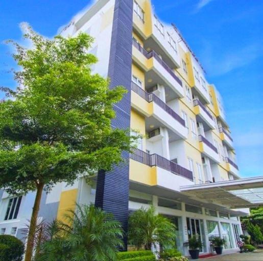 邦加槟港邦加城市酒店 的前面有一棵树的高楼