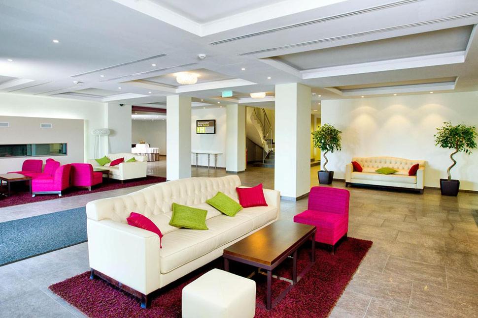 卡卢加卡卢加安布萨达酒店的客厅配有白色沙发和粉红色椅子