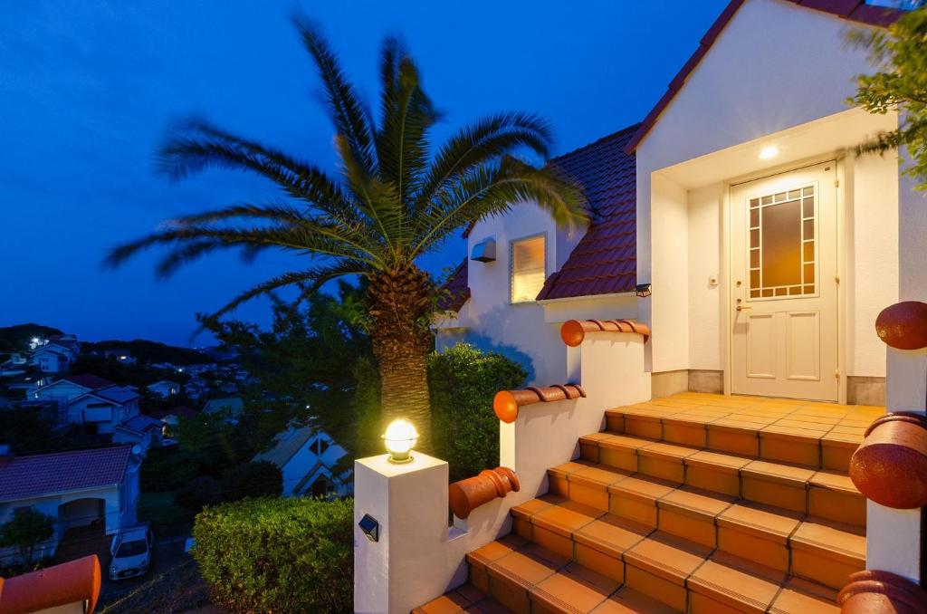 下田Bay Coast Villa Goishigahama - Vacation STAY 45736v的一座棕榈树的房子,楼梯上有一盏灯