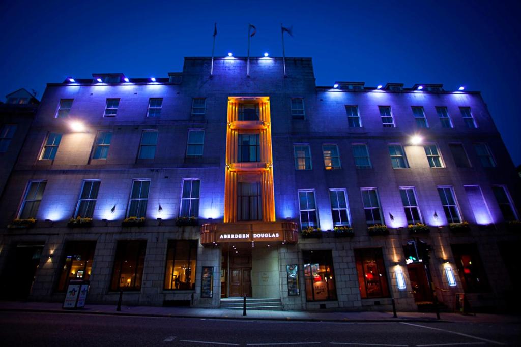 阿伯丁阿伯丁道格拉斯酒店的一座晚上点亮的建筑,蓝色和橙色