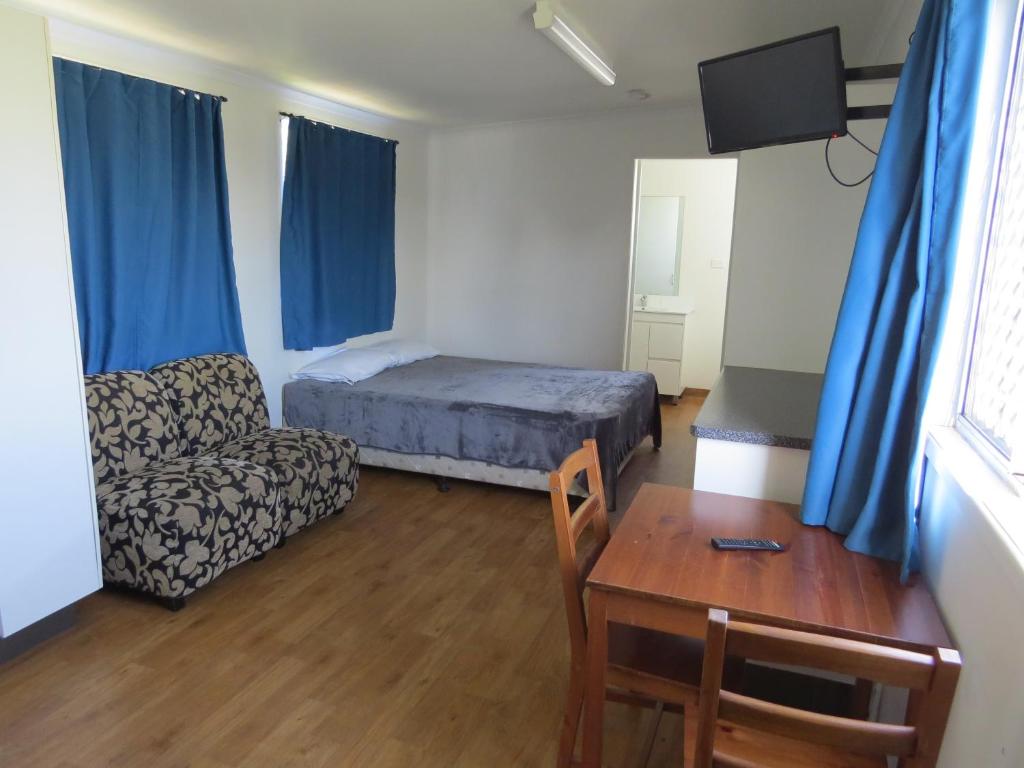 班达伯格Bundaberg East Cabin and Tourist Park的卧室配有1张床、1张桌子和1把椅子