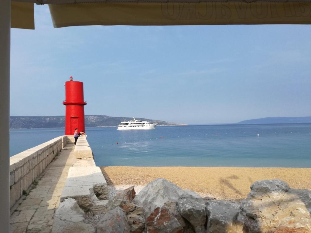 茨雷斯Guesthouse Romana的海滩上的红灯塔,水中有船