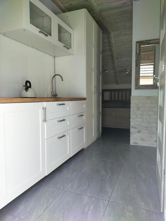 斯蒂格纳Apartament z tarasem的厨房配有白色橱柜和瓷砖地板。