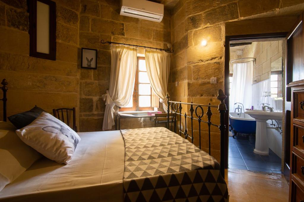 Tarxien陋居旅馆的一间卧室配有一张床,浴室设有水槽