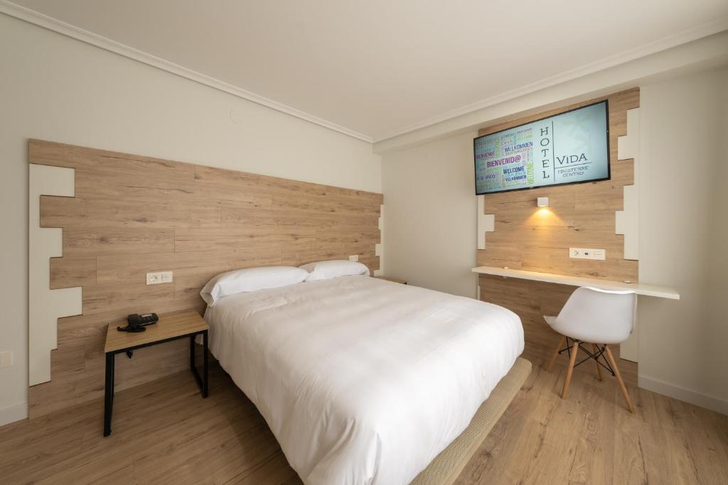 菲尼斯特雷Hotel VIDA Finisterre Centro的卧室配有一张白色大床和一张书桌