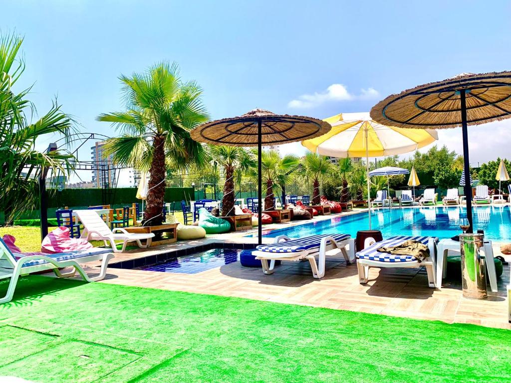 梅尔辛Vm Resort Otel Mersin的毗邻度假酒店的带椅子和遮阳伞的游泳池