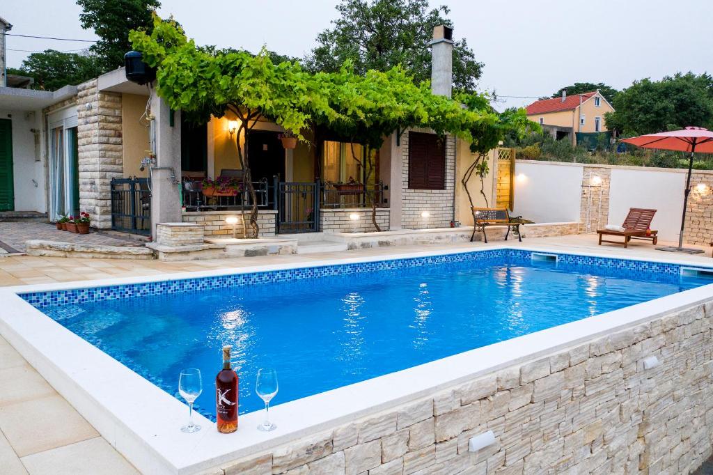 本科瓦茨Country House Korlat的一座游泳池,在房子前提供一瓶葡萄酒