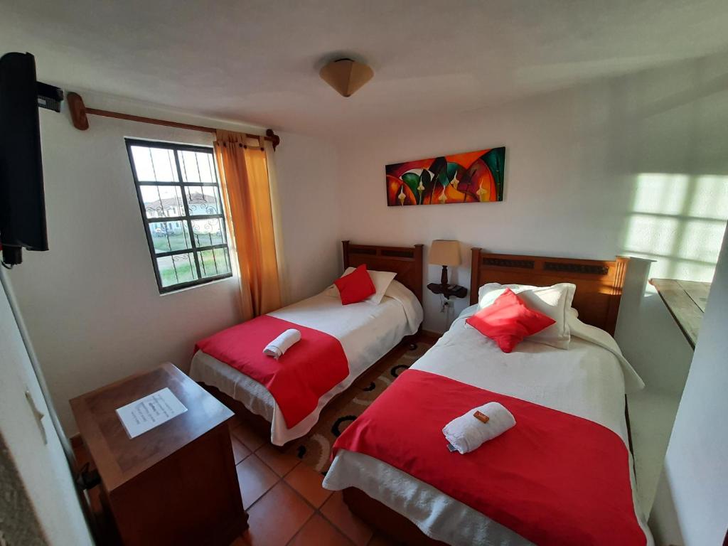 莱瓦镇Aparta Hotel El Refugio de María的一间设有两张红色和白色床单的房间