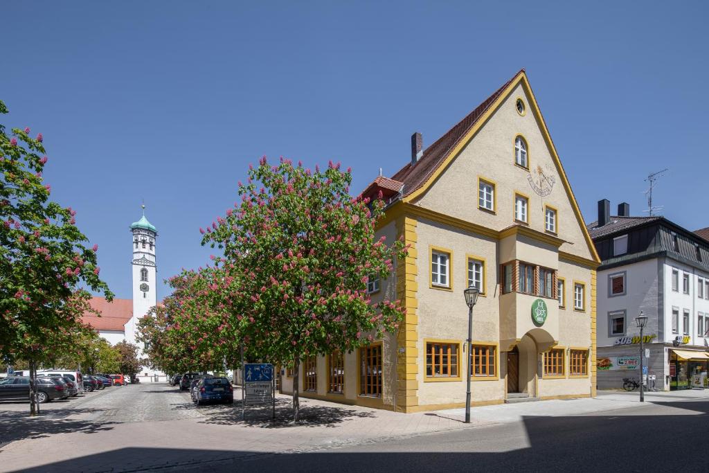 梅明根JOESEPP´S HOTEL am Hallhof的街道上一座黄色的建筑,有钟楼