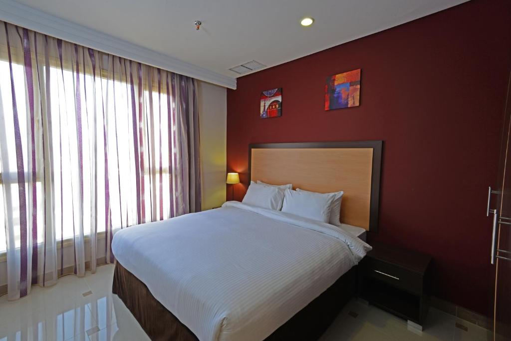 科威特贝努公寓的一间卧室设有一张带红色墙壁的大床