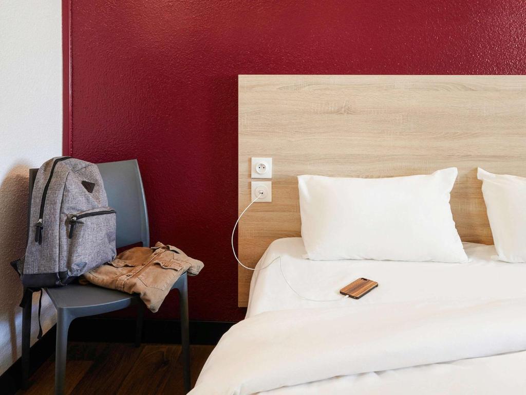 佩皮尼昂HotelF1 Perpignan Sud的一间卧室,配有一张床和椅子上的背包