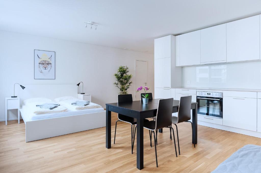 巴塞尔HITrental Messe Apartments的厨房以及带黑色桌椅的用餐室。