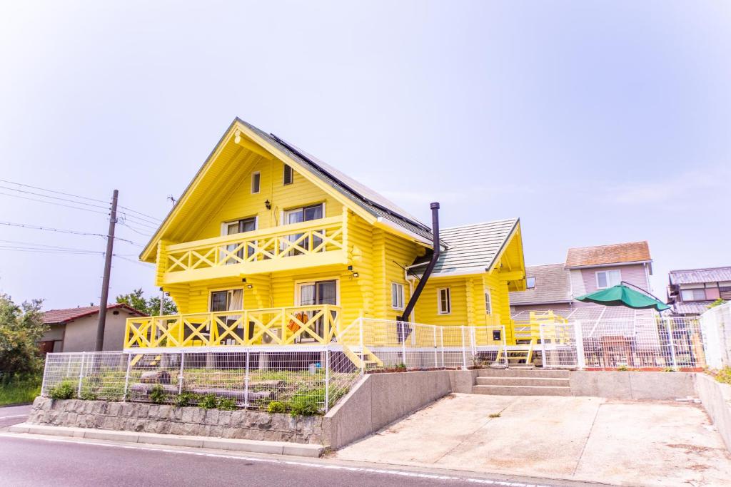 洲本市Awaji Large Log house in Goshiki的街道边的黄色房子