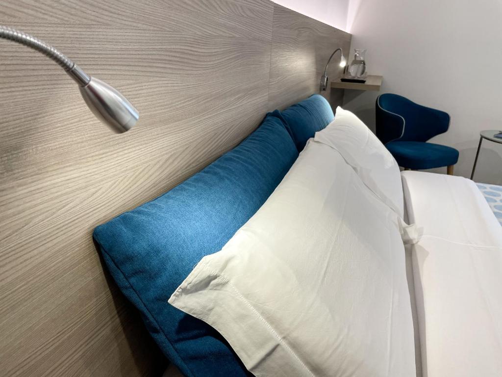 莱德罗Hotel Locanda Alla Perla的一张带蓝色和白色枕头的床和一盏灯