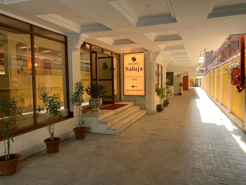 西里古里Hotel Saluja的建筑的走廊上,有盆栽植物
