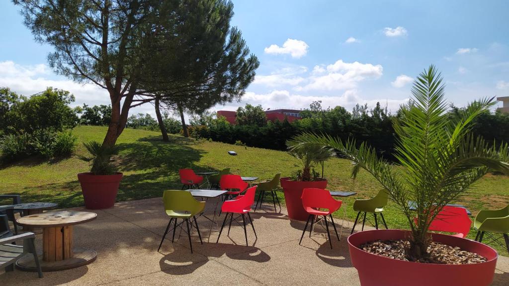 瓦朗斯樱桃瓦朗斯酒店的庭院设有红色和绿色的椅子和桌子。