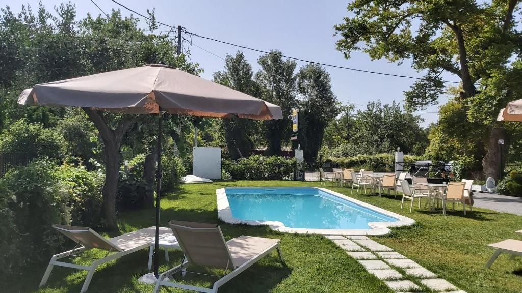艾斯普罗瓦塔斯泰利奥斯之家公寓的一个带遮阳伞和椅子及桌子的游泳池