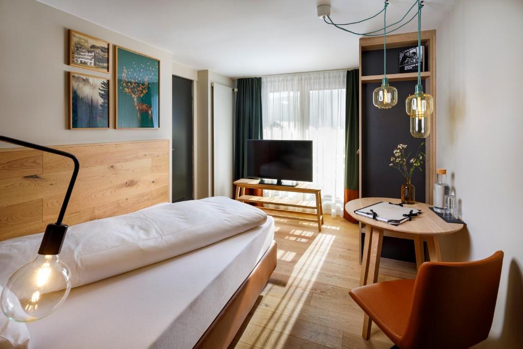 维尔德豪斯Hotel Hirschen Wildhaus的酒店客房设有床、桌子和电视。