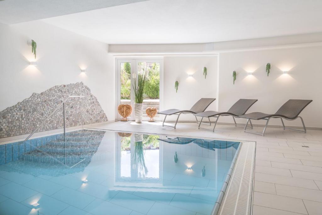 奥伯斯特多夫Hotel garni Gerberhof ***S的客房设有带椅子和桌子的游泳池。