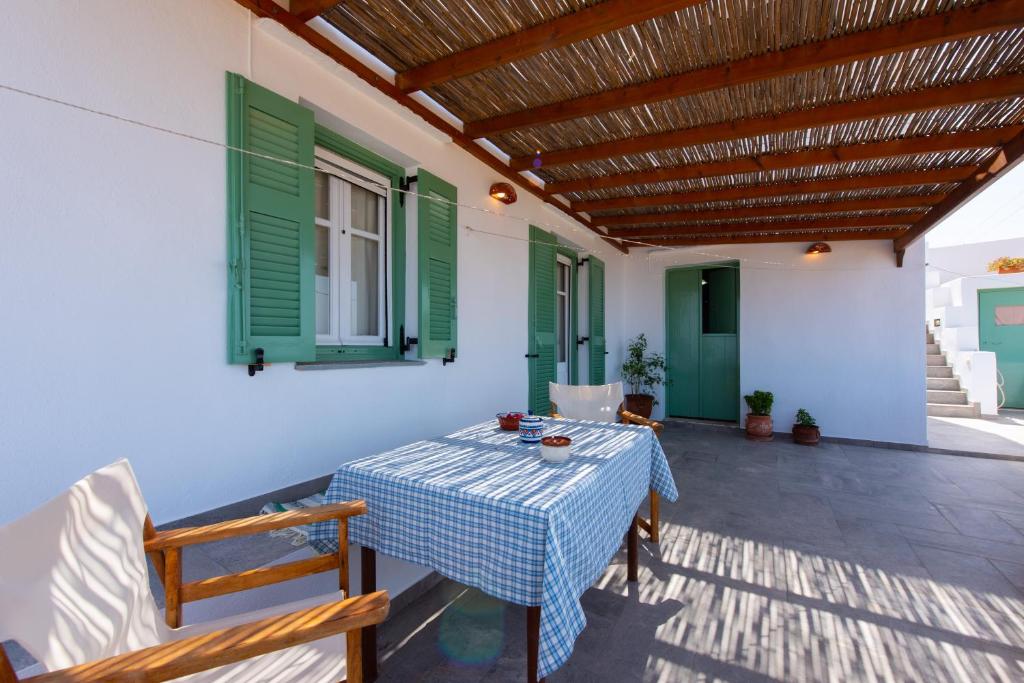 克若尼索斯«MARMARA» house的一个带桌子和绿色百叶窗的庭院