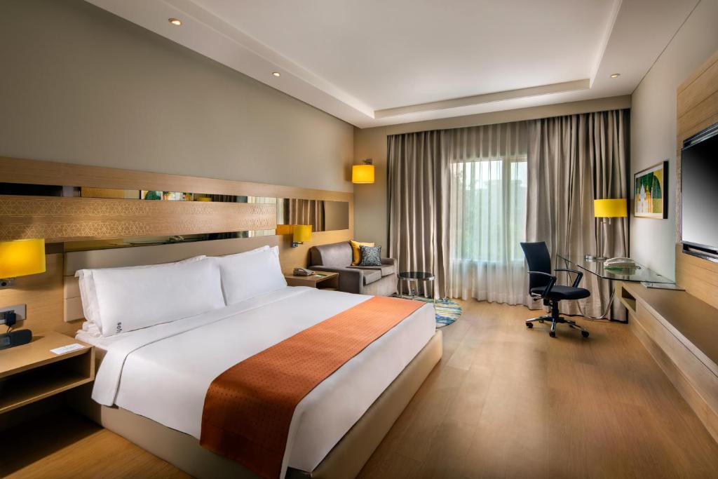 阿格拉Holiday Inn Agra MG Road an IHG Hotel的酒店客房设有一张大床和一张书桌。