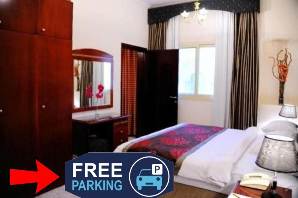 沙迦Al Sharq Hotel Suites - BAITHANS的一间卧室配有一张床,并拥有标志性的免费停车场