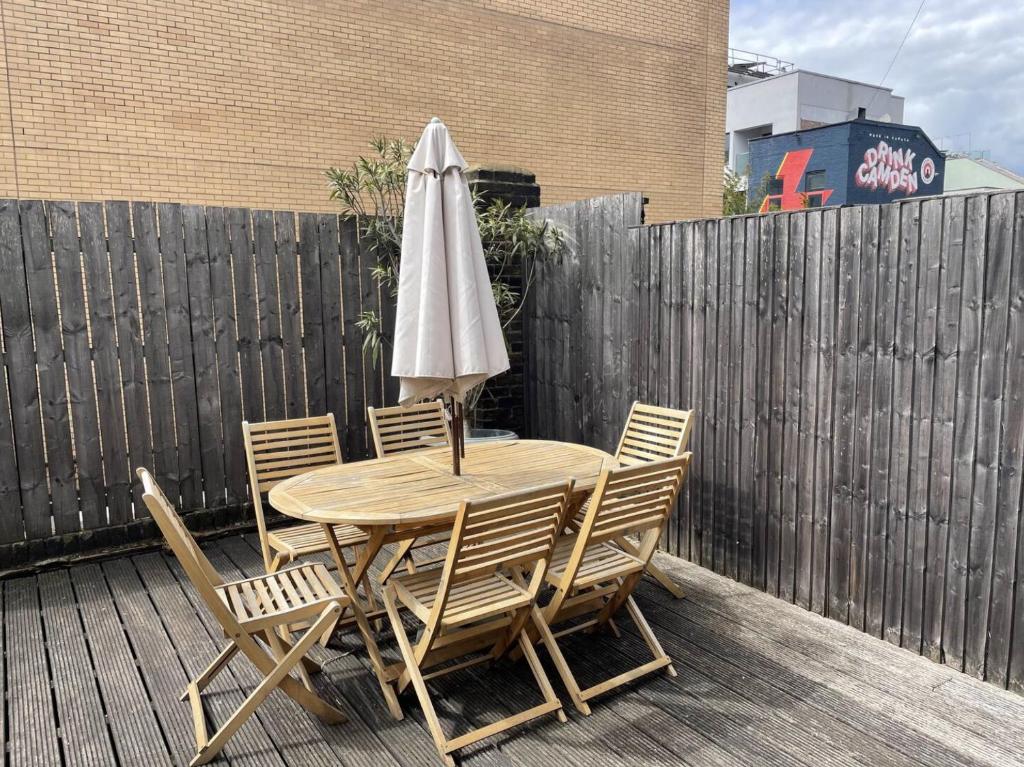 伦敦Central London Charming Camden Split Level Home的木桌和椅子,围栏上配有雨伞