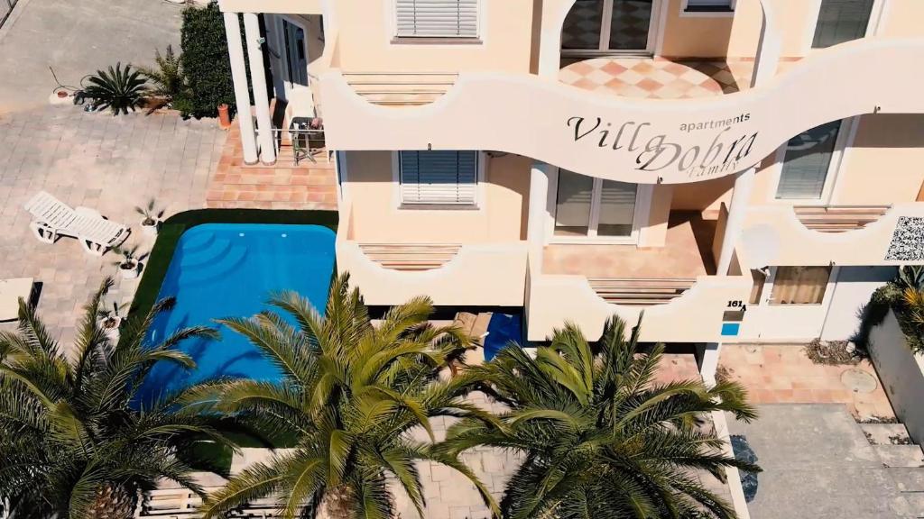 维尔Villa Dobra Family Apartments的享有棕榈树和游泳池建筑的空中景致