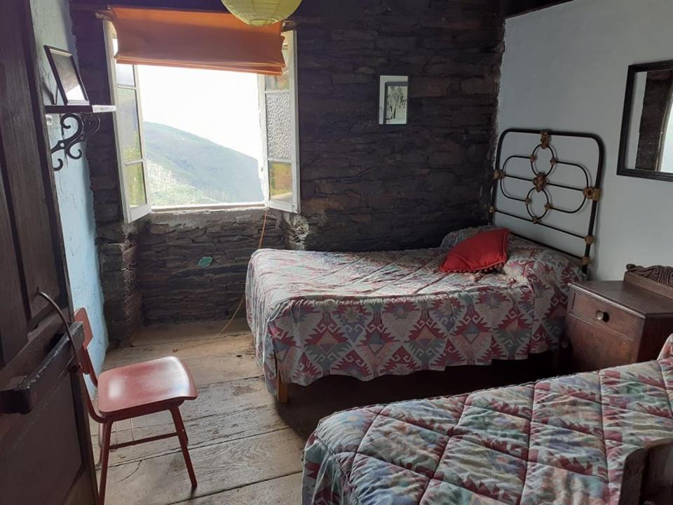 卢戈Albergue ESCANLAR的一间卧室设有两张床、一把椅子和一个窗户。