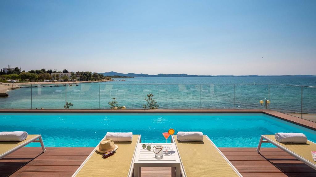扎达尔Dedaj Resort - Villa Tina的一个带两把椅子的游泳池,享有水景