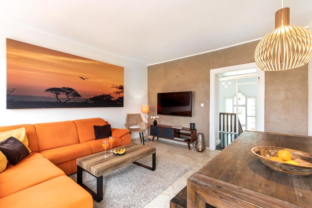 辛根PRIMERA Villa的客厅配有橙色沙发和桌子