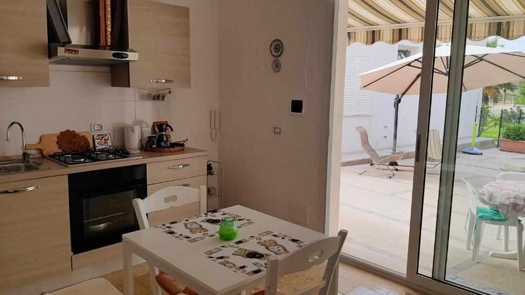 奥尼纳Casa Mare Ognina的一间带桌子的厨房和一间带雨伞的用餐室