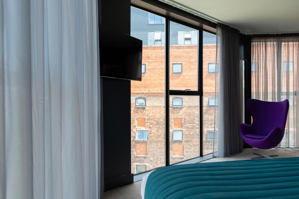 利物浦The Baltic Hotel的一间卧室配有紫色椅子和大窗户