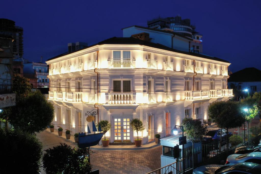 都拉斯Giulia Albérgo Hotel的一座白色的大建筑,晚上有灯光