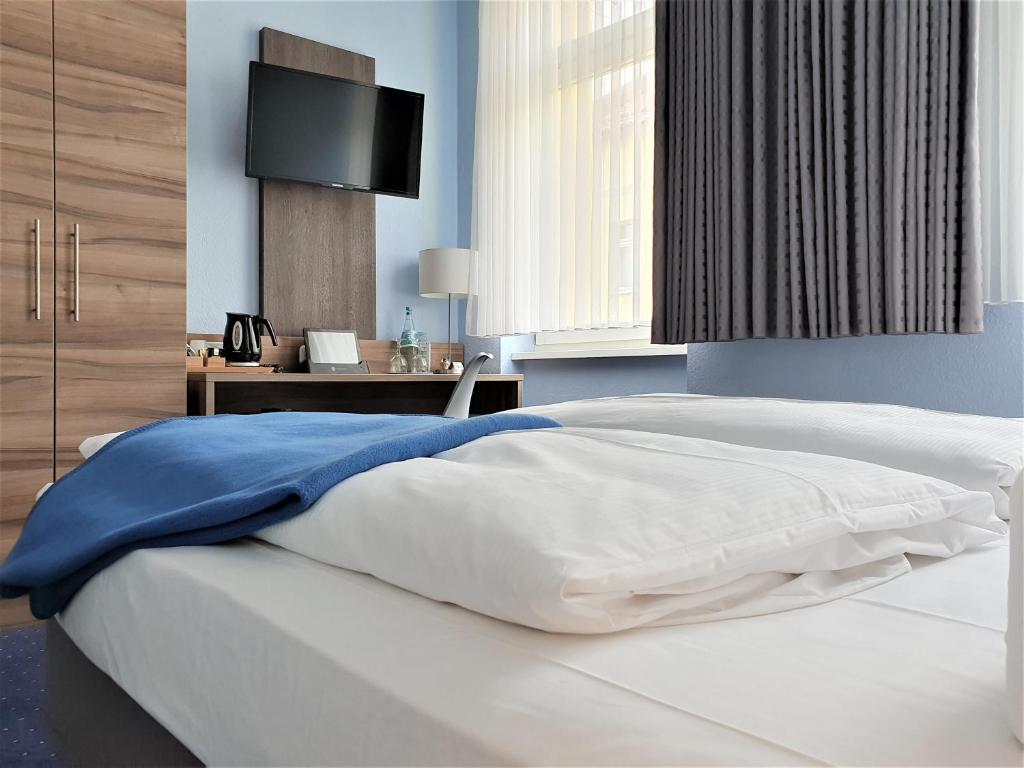 柏林梅拉罗斯·芬·舒酒店的卧室配有白色的床,墙上配有电视