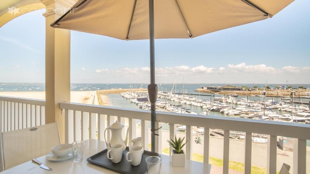 阿卡雄Epsom - Appartement en front de mer Arcachon的阳台配有带雨伞的桌子和码头