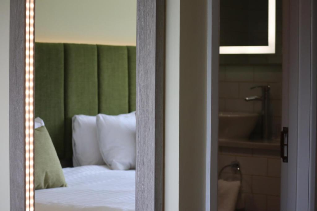 达文特里海里顿雷克斯度假村的一间卧室配有一张带绿色床头板的床和浴缸