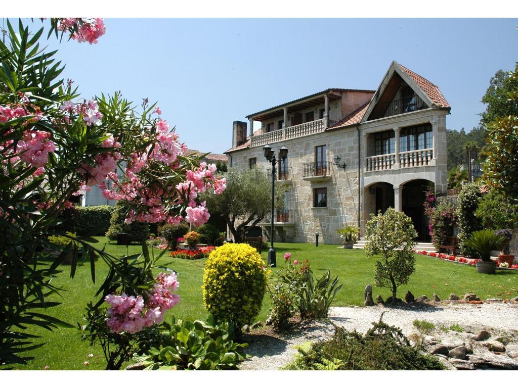 Lestrove卡萨安蒂加杜蒙特酒店的一座老石头房子,在院子里种有粉红色的花