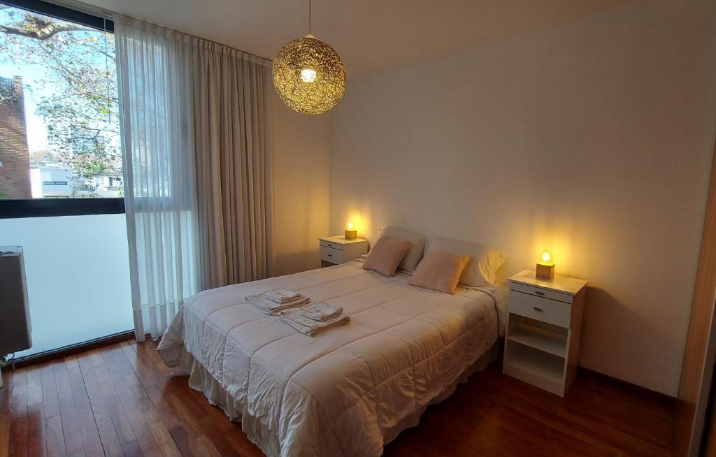 罗萨里奥Cálido y hermoso Dpto. en excelente zona de Rosario的一间卧室配有带2个床头柜和2盏灯的床